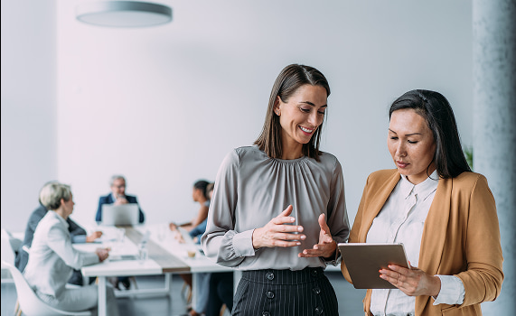 Deux personnes regardent une tablette en souriant dans un environnement de travail